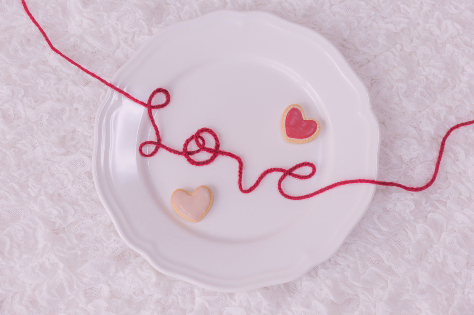 丸皿の上に赤い糸でLOVEの文字とハートクッキー