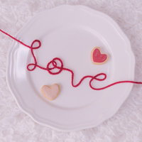 白い丸皿の上に赤い糸で描かれたLOVEとハートの写真