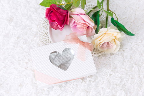 ハートのカードに添えたバラの花と告白のプレゼント
