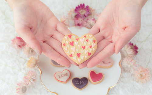 愛を込めた手作りハートクッキーをそっと包み込む両手