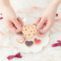 両手でつまんだハート型の手作りクッキー、バレンタインギフトの写真