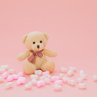 ピンクと白のハートに囲まれたクマのぬいぐるみの写真
