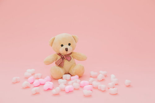 ピンクと白のハートに囲まれたクマのぬいぐるみ