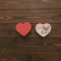木製テーブルに置かれたハート型の箱とリボンの写真