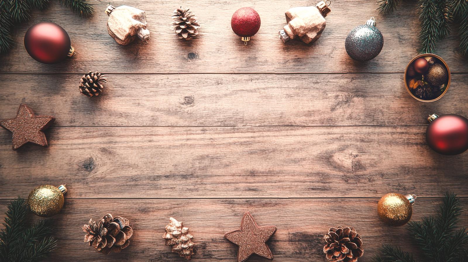 木製テーブルの上に赤や金色のクリスマスオーナメント、松ぼっくり、星型装飾が配置されている