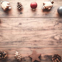 木製テーブルに並ぶクリスマスオーナメントと松ぼっくりの装飾の写真