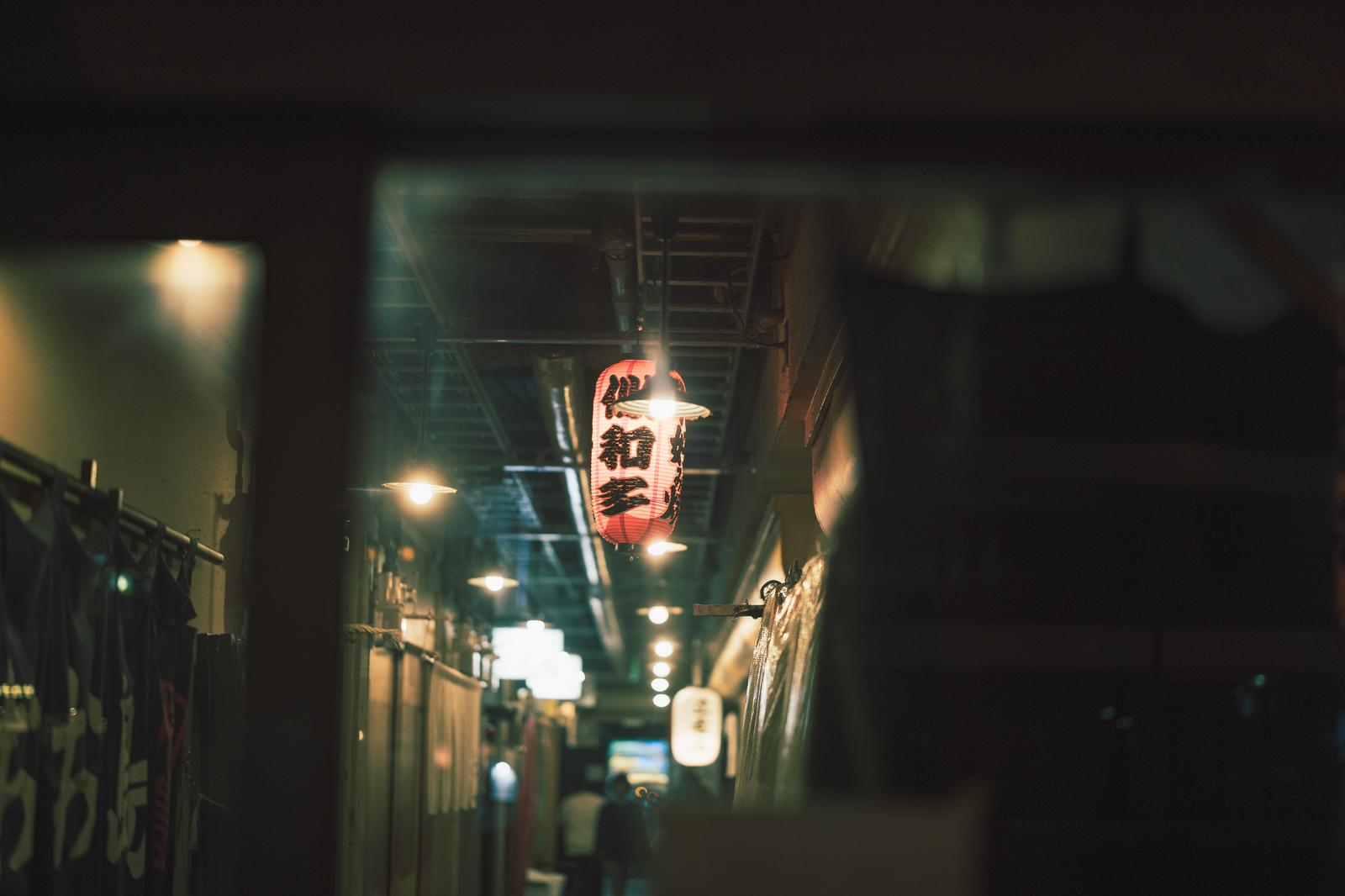 赤と白の提灯が吊された夜間の路地裏の居酒屋街