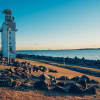 夕焼けに染まる若洲海浜公園の海岸と灯台の写真