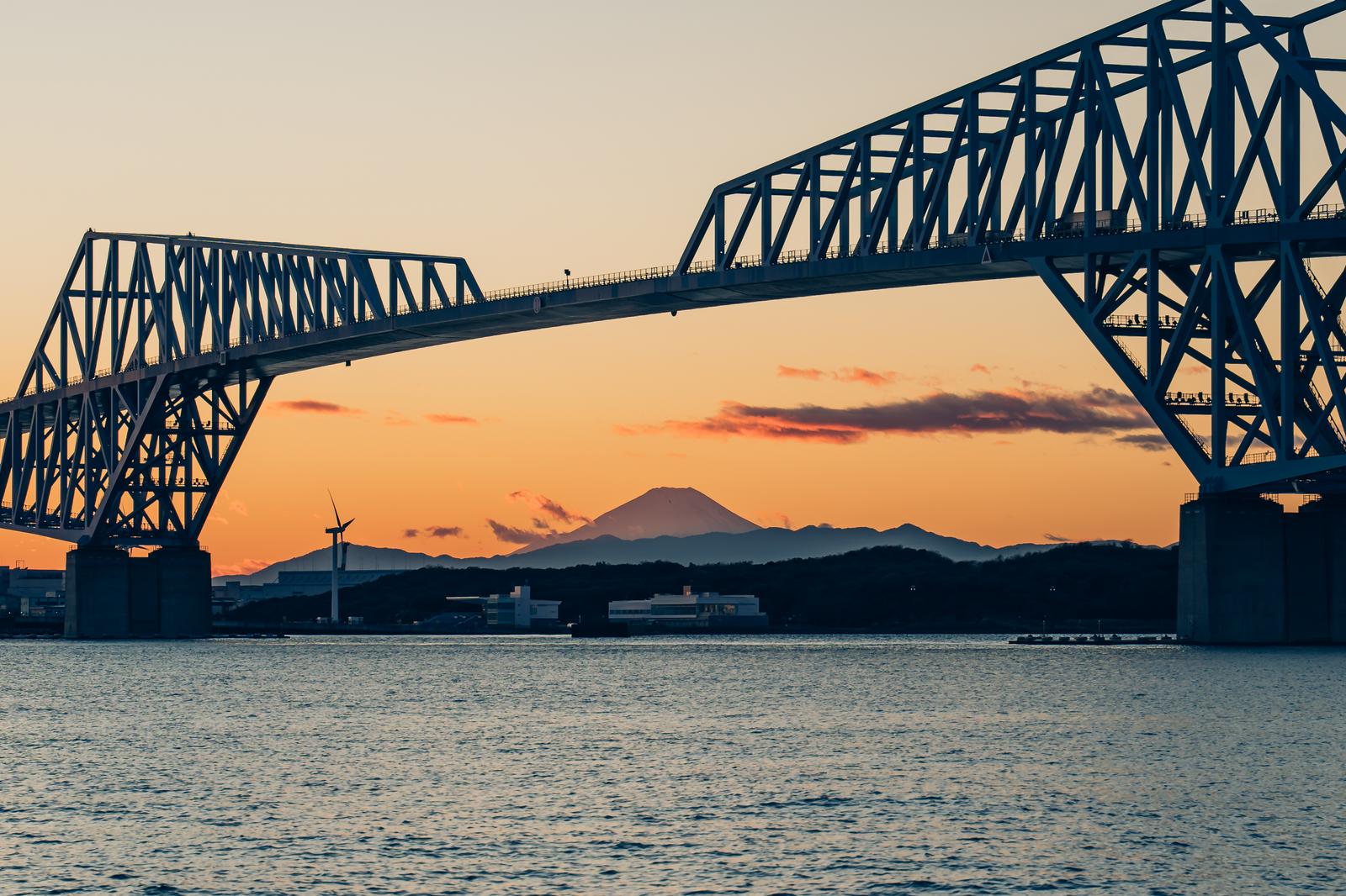 夕焼けの空を背景にゲートブリッジと富士山が見える東京湾の風景