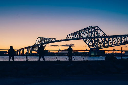 若洲海浜公園からゲートブリッジと夕焼けを撮影するフォトグラファーたちのシルエット
