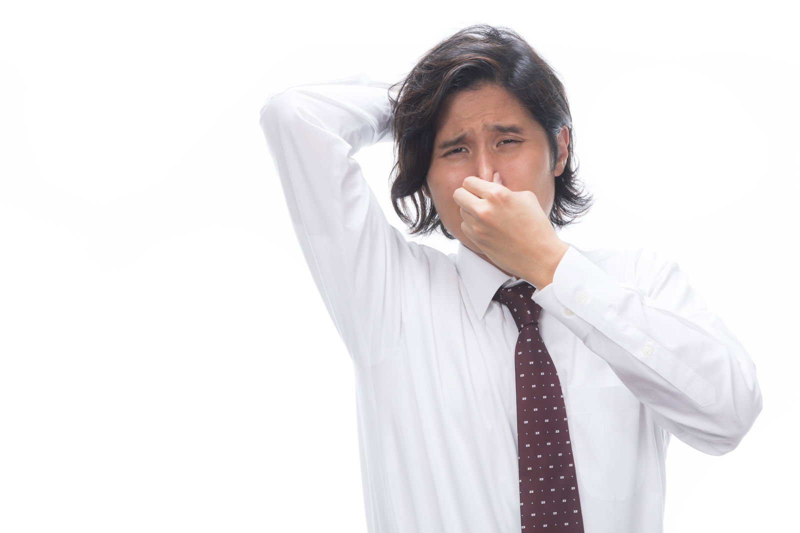 鼻をつまんで顔をしかめる白いワイシャツとネクタイ姿の男性会社員［モデル：竹田匡宏］