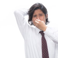 体臭に鼻をつまむ男性会社員のワイシャツ姿の写真