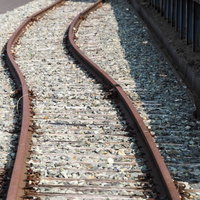仙石線旧野蒜駅前の湾曲した線路と震災遺構の写真