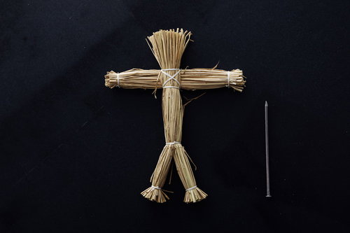 五寸釘と藁の人形を黒背景に配置した恐怖と怨念の演出