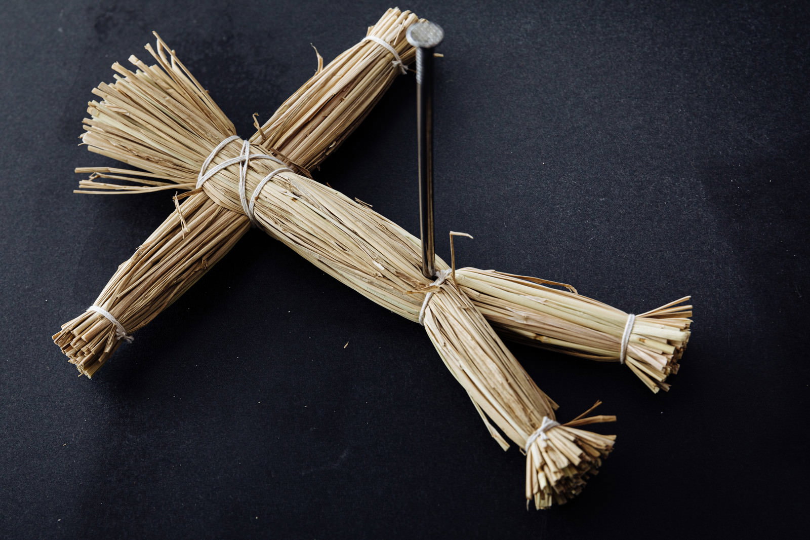 黒い背景に置かれた藁人形と五寸釘