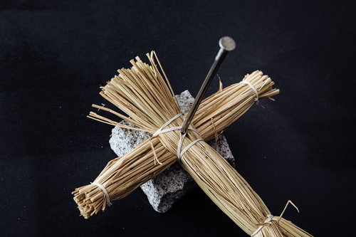 黒い背景に五寸釘を打ち込んだわら人形の