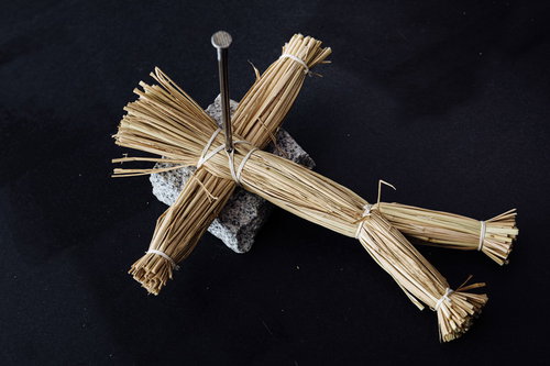 五寸釘が十字に刺さった藁人形の呪い - 黒背景の怨念表現