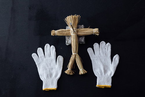 黒い背景に配置した藁人形と五寸釘、軍手を使った呪い演出