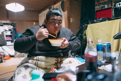 自宅の汚部屋でラーメンを啜る無精髭の男性