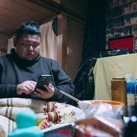 スマホで追い注文する肥満男性の汚部屋での食生活の写真