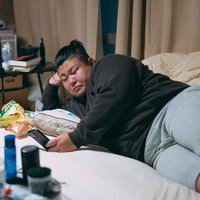 肘枕でスマホを眺めるぐうたら男性の写真