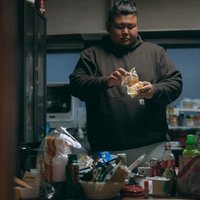 汚れた台所で袋入りのお菓子を食べる160キロ男子の写真