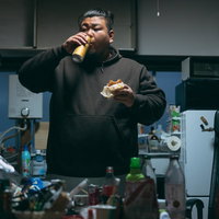 散らかったキッチンで立ち飲みする男性の写真