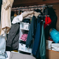 衣類で埋まった取り散らかしたハンガーラックの写真