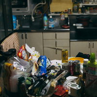 空き缶やゴミが散乱した汚部屋のキッチンの写真