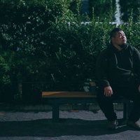 公園のベンチで上を向いて待ちぼうけの男性の写真