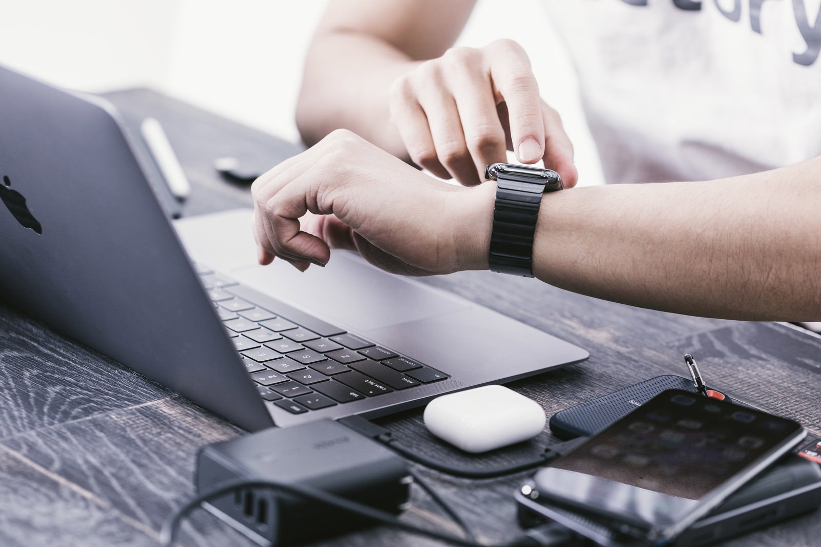 デスクでノートパソコンを使いながらApple Watchの通知を確認するエンジニアの手元