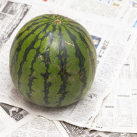 新聞紙の上に置いた西瓜一玉の写真