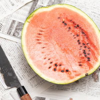 赤い果肉が見える西瓜を包丁で半分に切った瞬間の写真