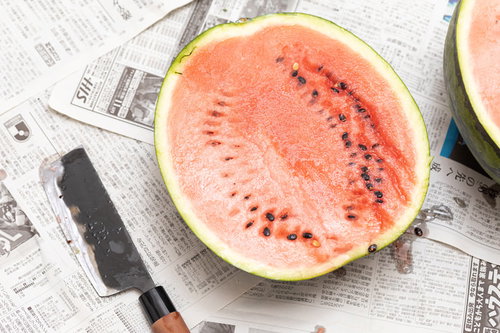 赤い果肉が見える西瓜を包丁で半分に切った瞬間