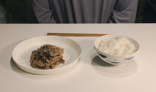 白い皿に盛られた牛肉の煮物と茶碗のご飯