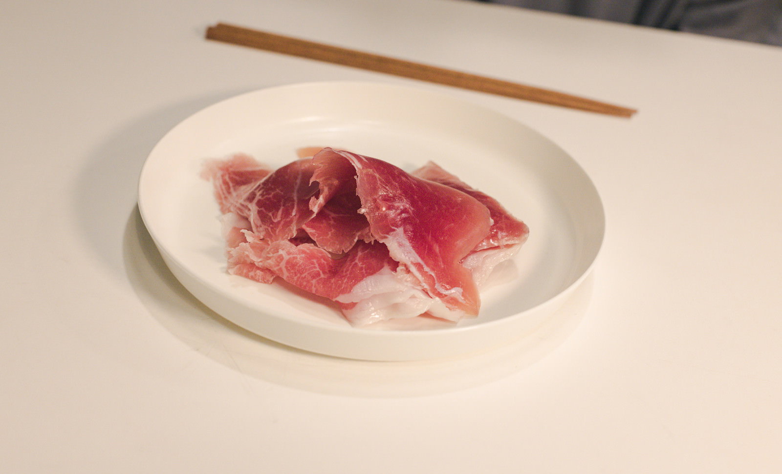 白い皿の上に置かれた赤い生の牛肉