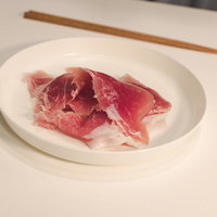 白い皿に盛られた生肉、調理前の新鮮な赤身牛肉の写真