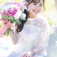 ピンクのブーケを持った笑顔の花嫁のウェディングドレス姿の写真