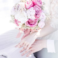 ピンクと白のバラが入ったウエディングブーケを持つ新郎新婦の写真