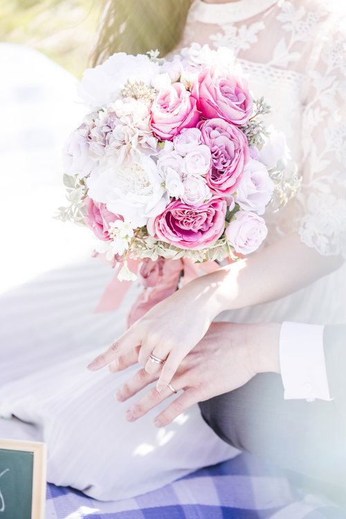 ピンクと白のバラが入ったウエディングブーケを持つ新郎新婦