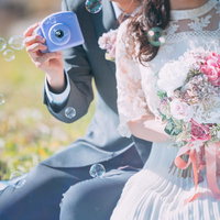 シャボン玉を吹く新郎新婦とピンクのウエディングブーケの写真