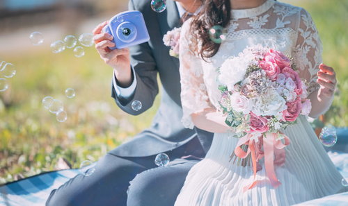 シャボン玉を吹く新郎新婦とピンクのウエディングブーケ