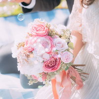 ウェディングドレスの花嫁が持つピンク色のバラのブーケとシャボン玉の写真