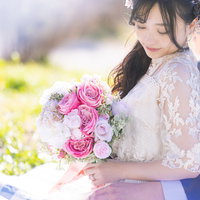 ピンクのバラのブーケを持つ白いウェディングドレスの花嫁の写真