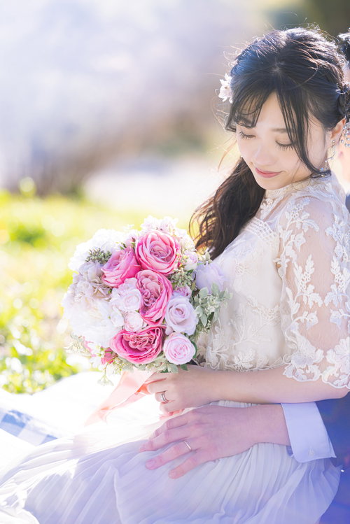 ピンクのバラのブーケを持つ白いウェディングドレスの花嫁