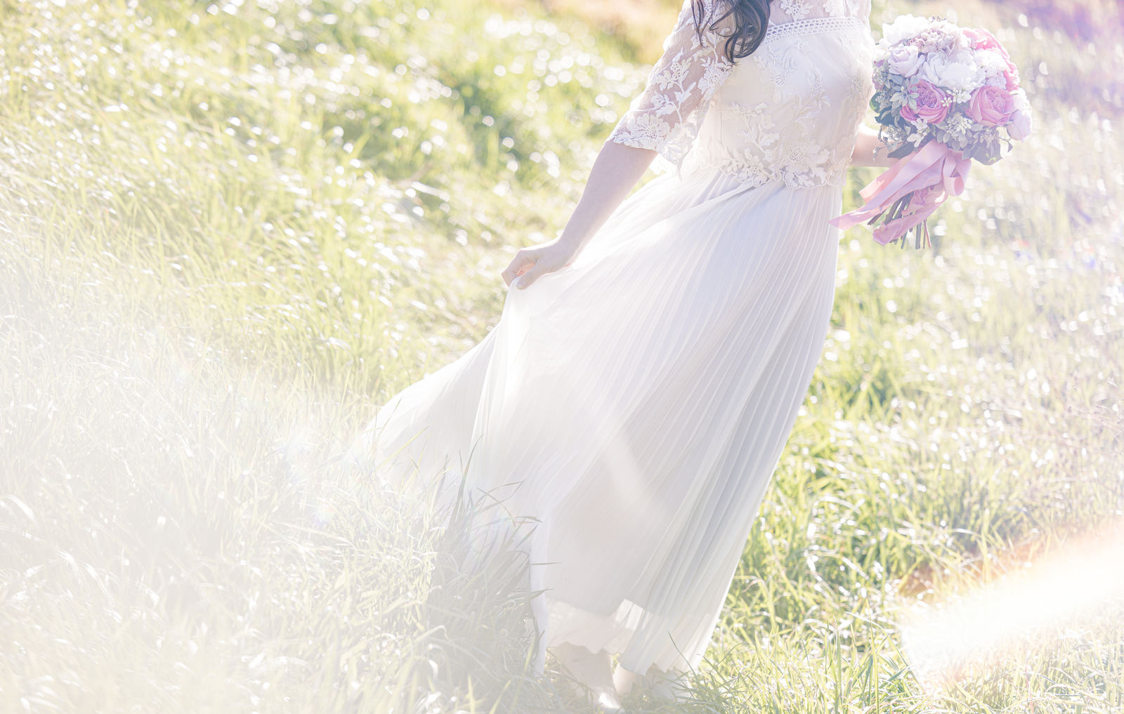 新緑の丘で白いレースドレスとピンクのブーケを持つ花嫁［モデル：河村友歌］