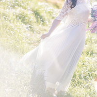 新緑の丘でブーケを持つ白いウエディングドレスの花嫁の写真