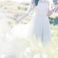 光が降り注ぐ野原でブーケを持つ花嫁の後ろ姿の写真