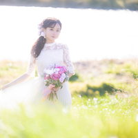 春の野原でブーケを持つ花嫁のウェディングドレス姿の写真