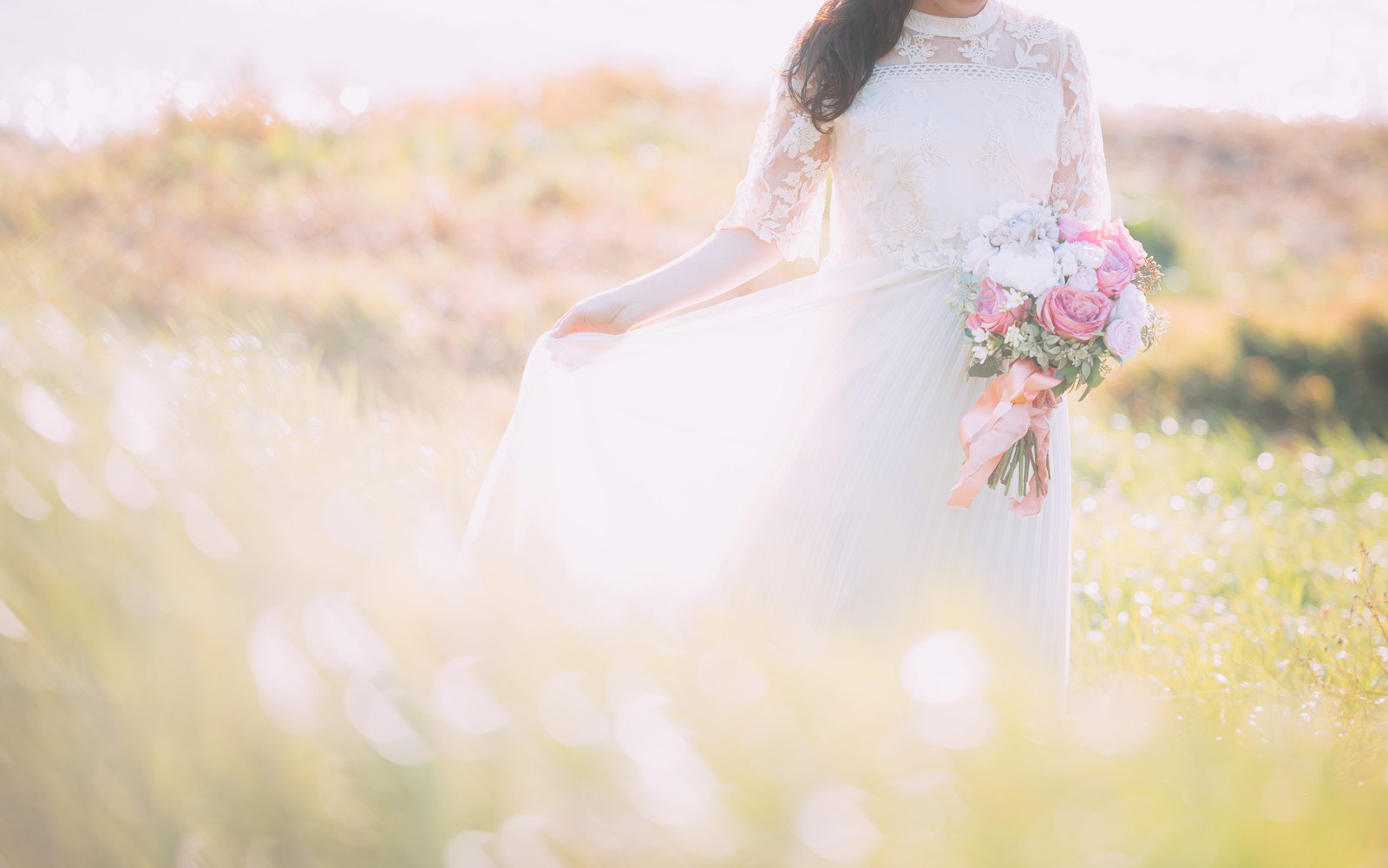 ピンク色のバラのブーケを持つ白いレースのウェディングドレス姿の花嫁［モデル：河村友歌］